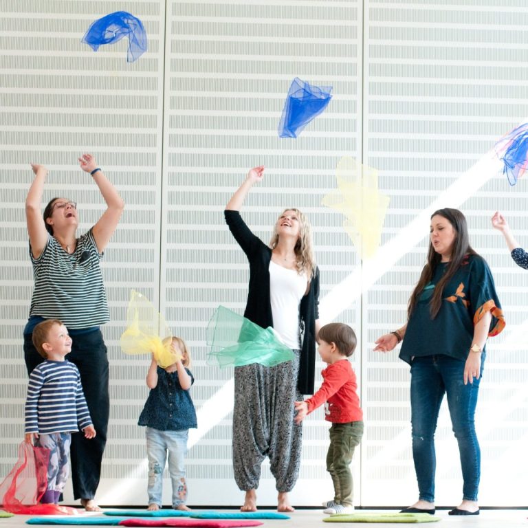 Ein Tüchertanz Kinder und Erwachsene werfen stehend Tücher in die Luft und beobachten gespannt.